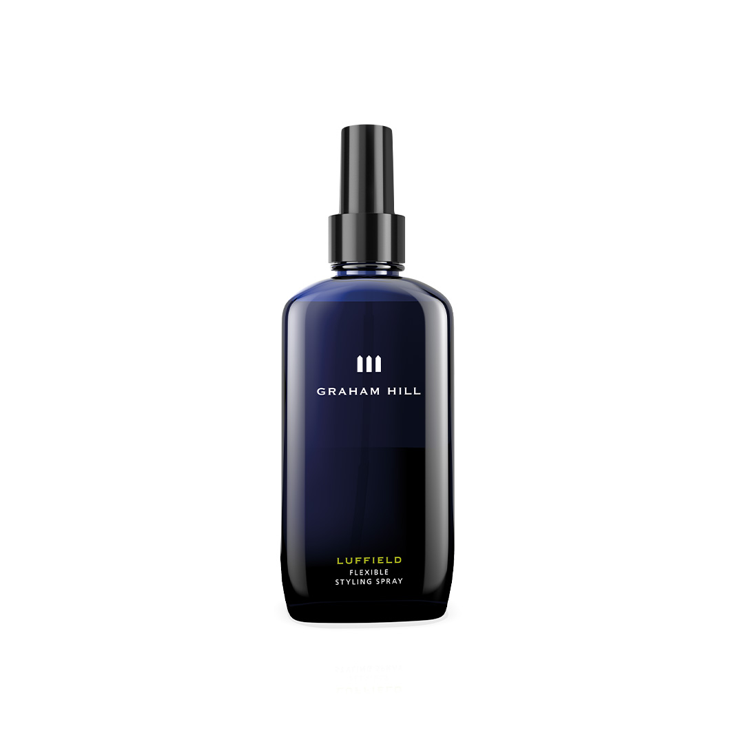 Extra stark festigendes LUFFIELD Flexible Styling Spray von GRAHAM HILL in einer dunkelblauen 200-ml-Sprühflasche mit schwarzem Pumpaufsatz